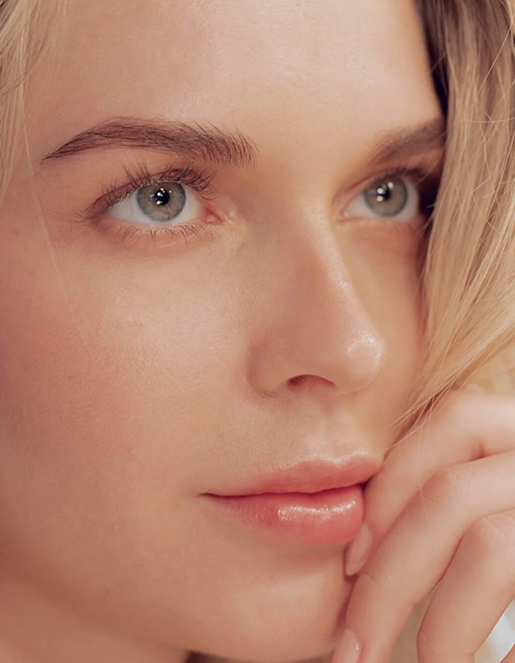 Close-up of a person with light skin and blonde hair, wearing a white shirt.
